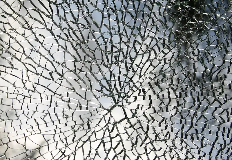 Vidro trincado em forma de teia, com as rachaduras partindo de um ponto central