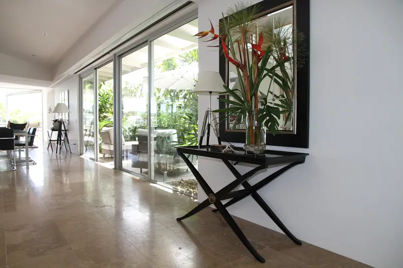 Sala com piso claro e portas de vidro abertas para um jardim